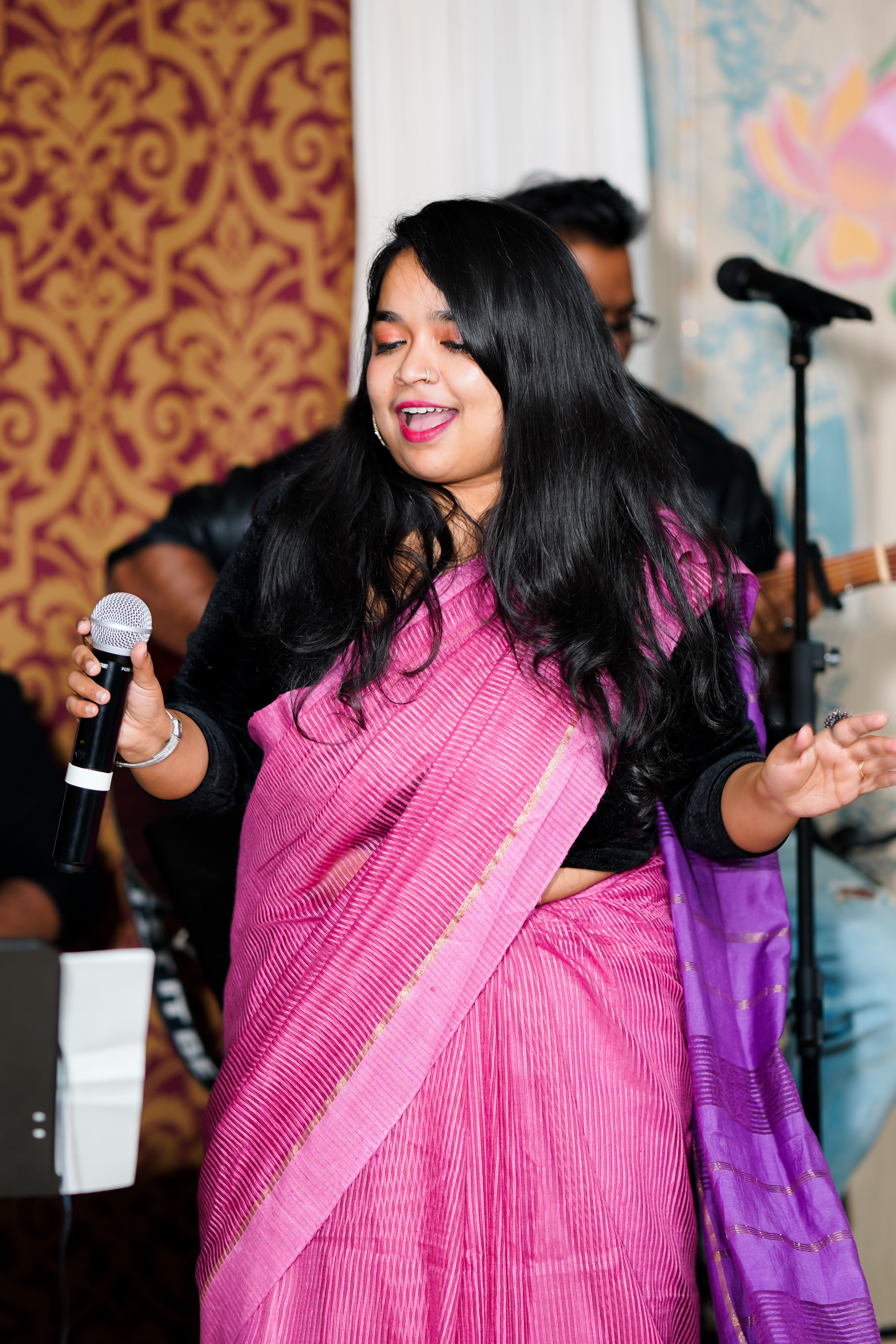 Sukanya Chakraborty performing on stage in a magenta saree.
