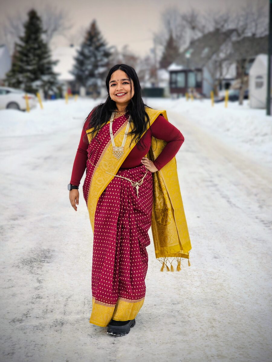 Sukanya Chakraborty smiling, dressed in a maroon and gold sari